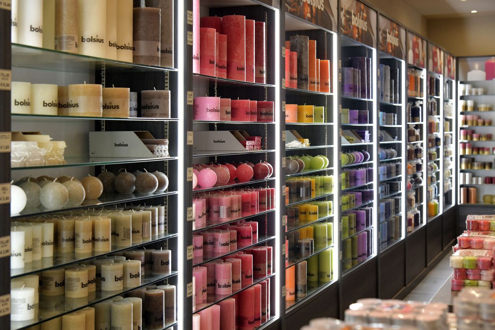 A wall of shelves filled with candles in many colors