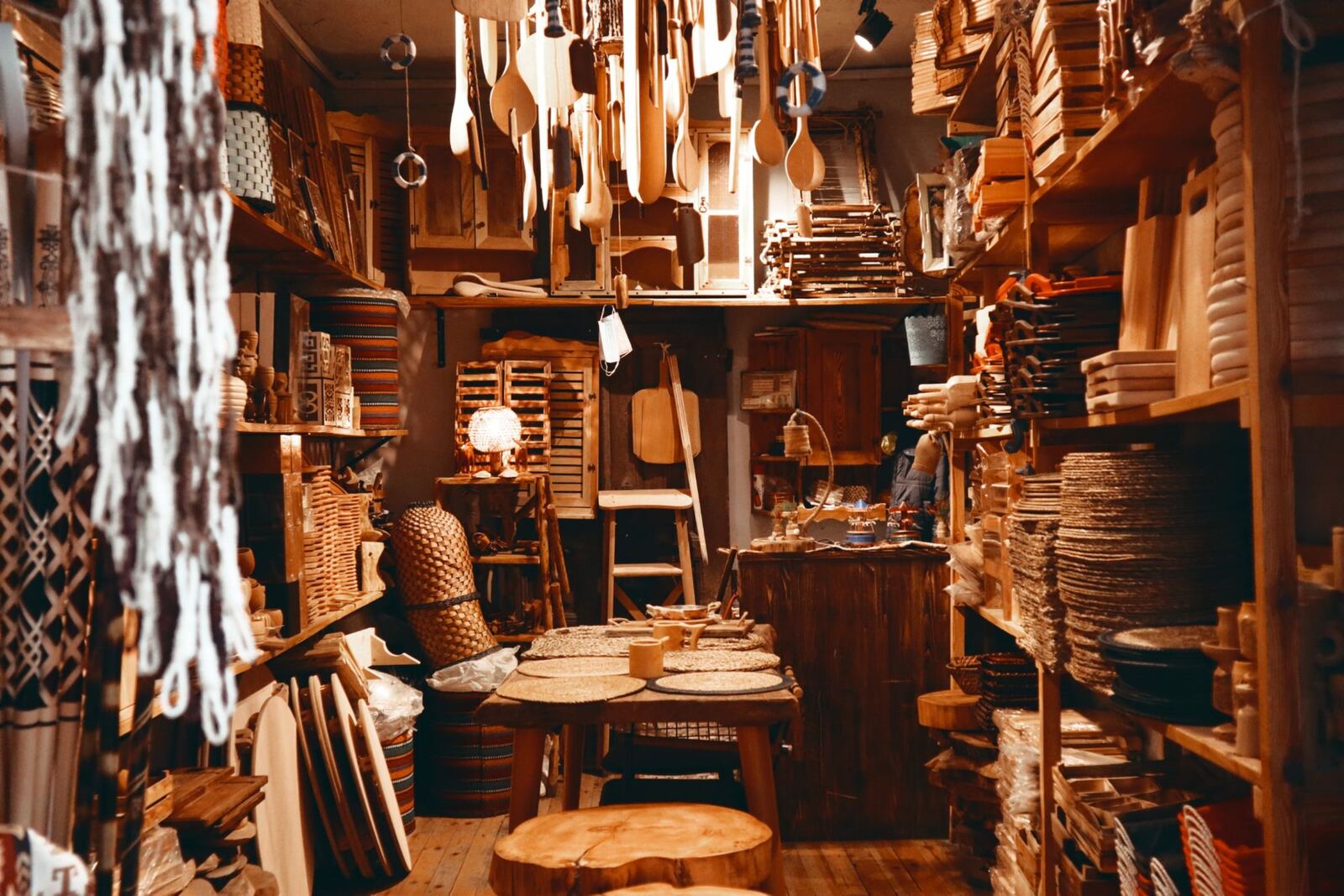 Shelves of wooden kitchen tools and baskets in a warmly lit shop