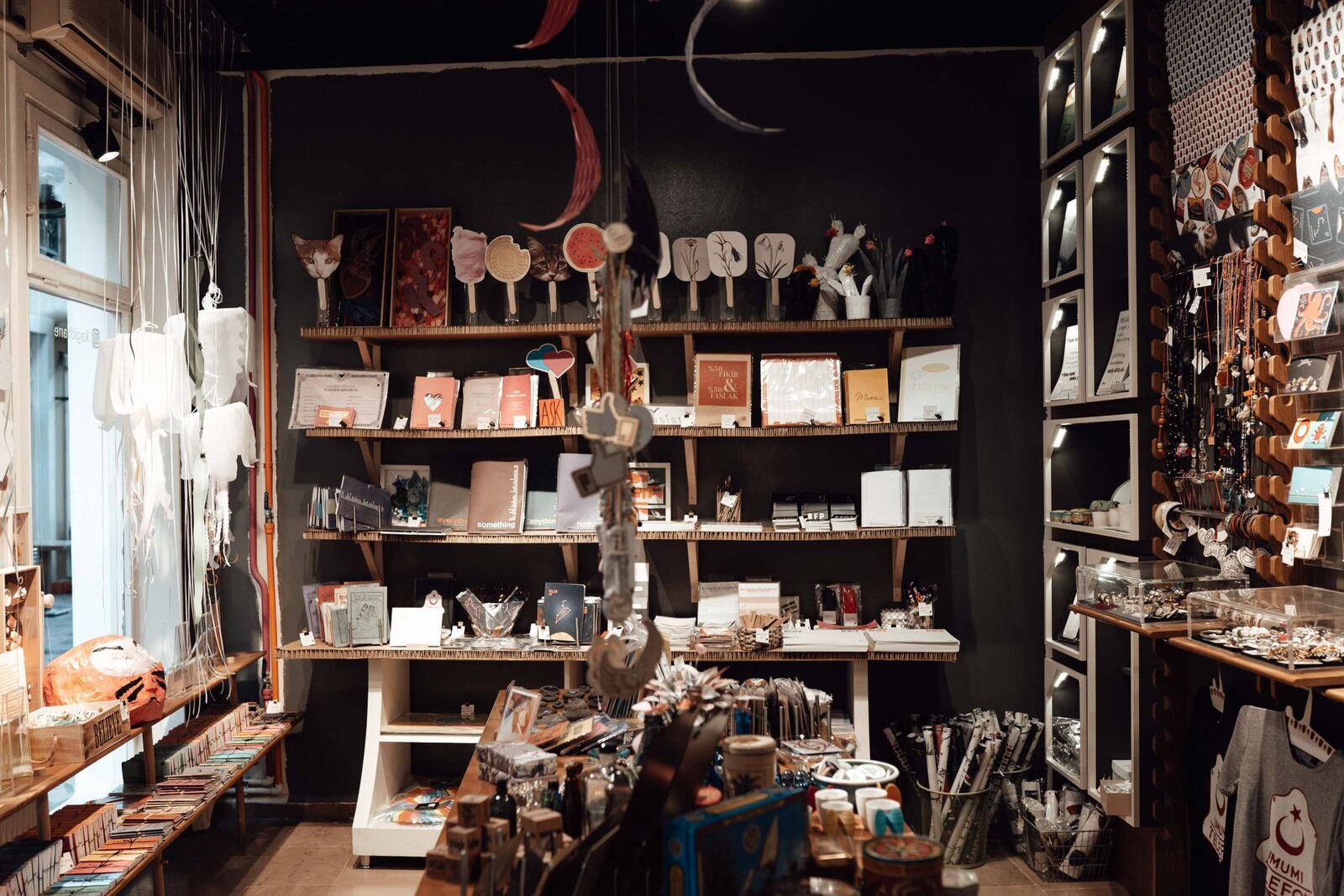Wooden shelves crowded with gifts, cards and ceramics in the front room of the shop