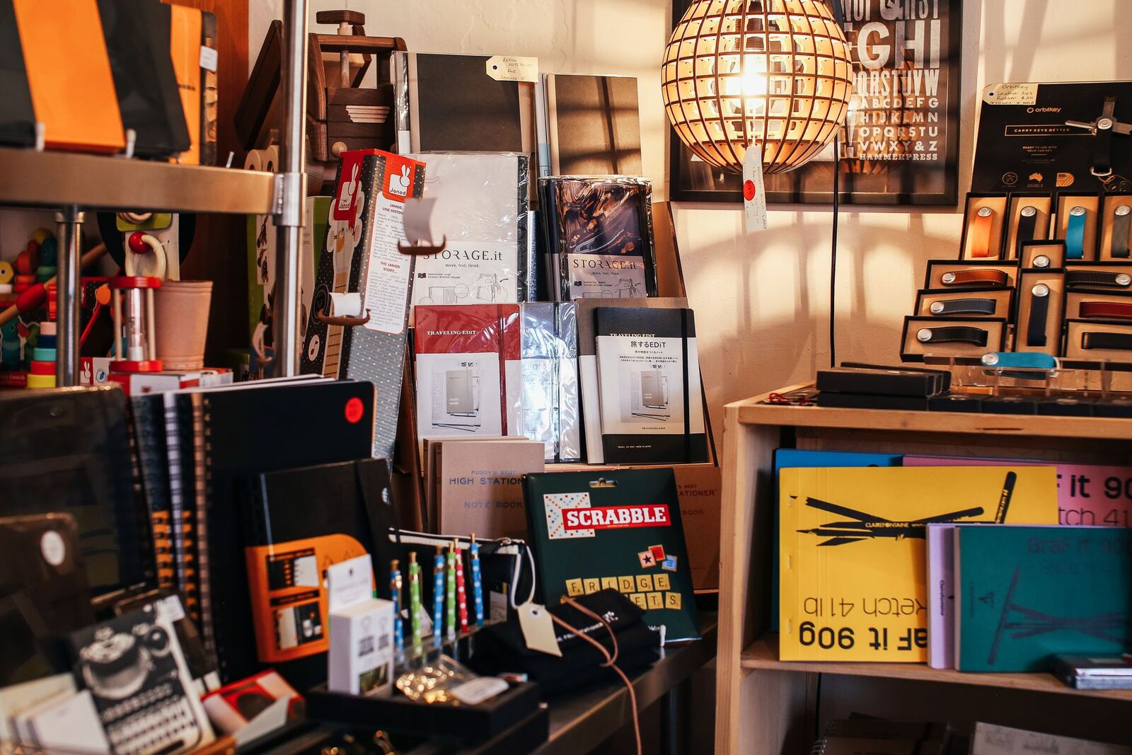 Notebooks, pens and games on shelves under a hanging lamp